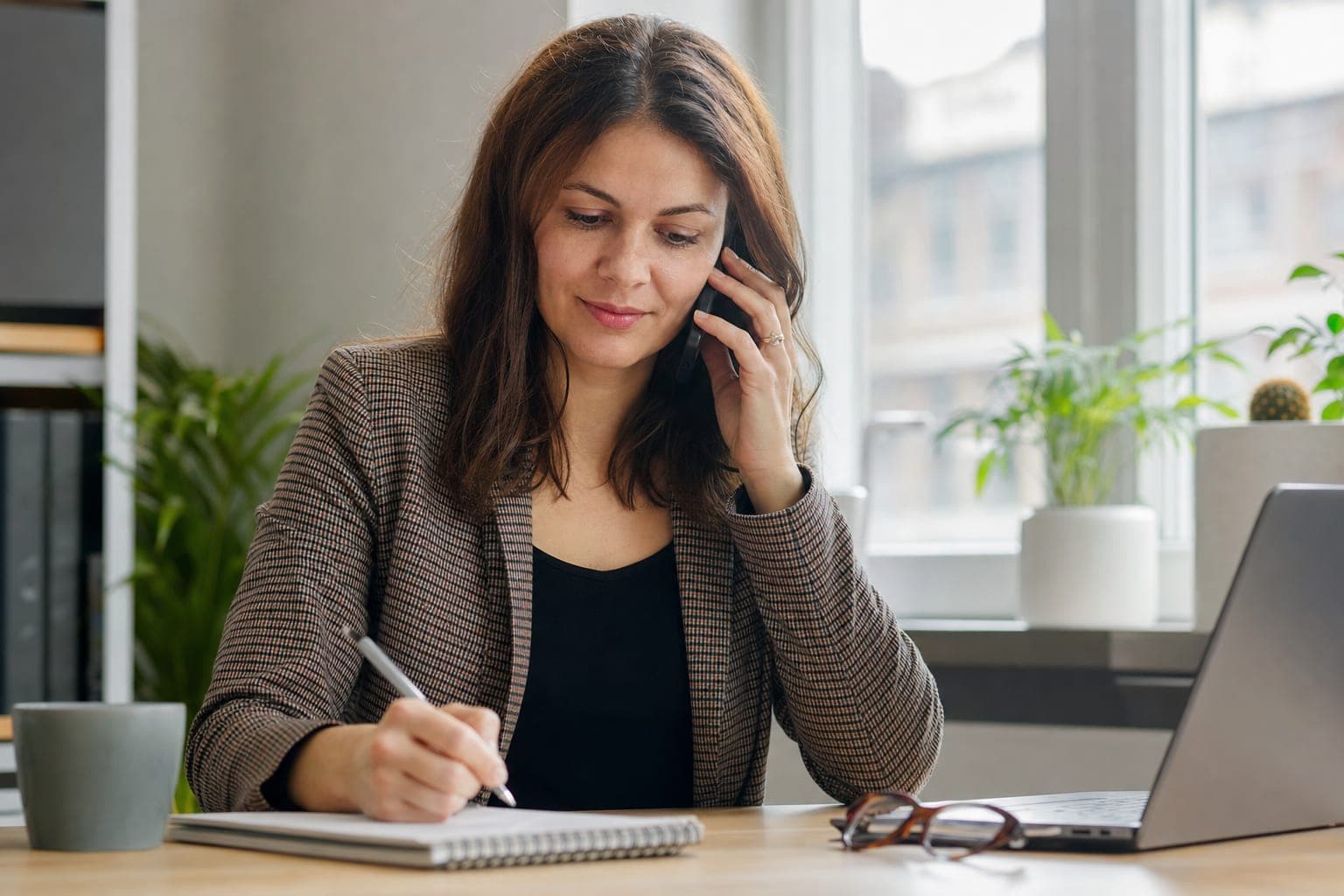 Recruiterin im Telefonat mit Notizblock am Schreibtisch